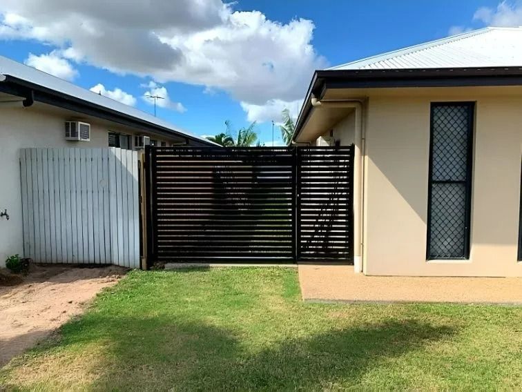Black Horizontal Slat Gate Between Two Buildings, Green Lawn in Front — Gate-O-Matic in Garbutt, QLD