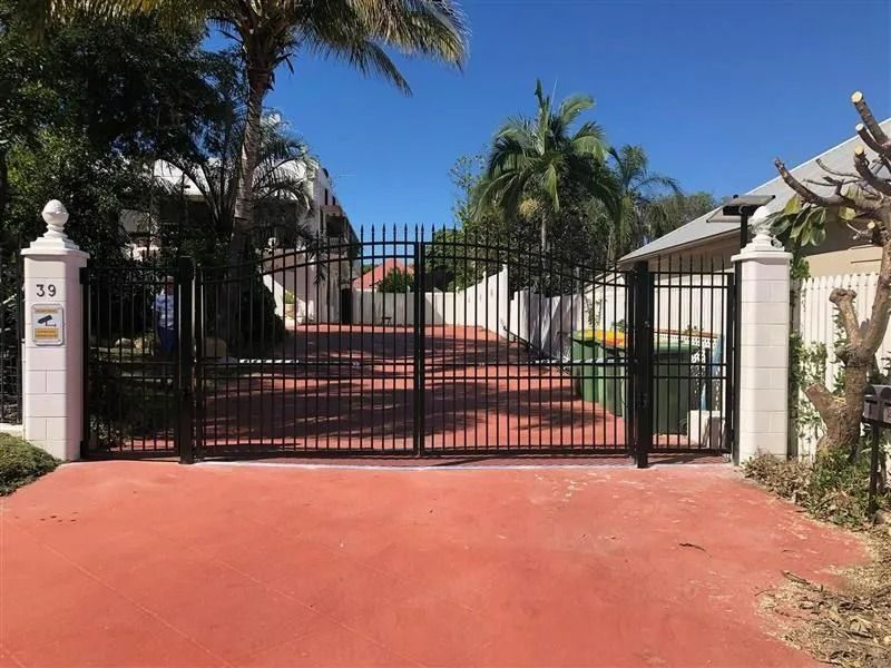 a Black Metal Driveway Gate Stands Between Two White Pillars — Gate-O-Matic in Garbutt, QLD