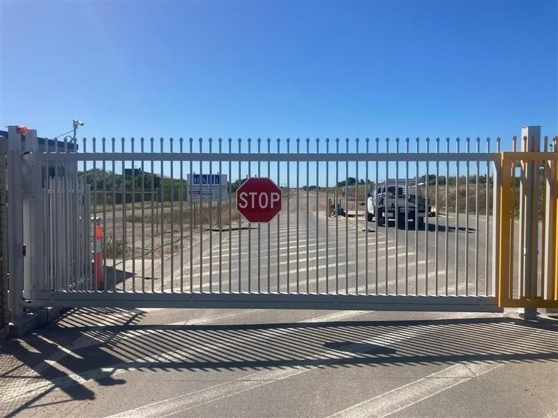 Closed Metal Gate With a Stop Sign, Leads to a Gravel Road With a Parked Vehicle — Gate-O-Matic in Garbutt, QLD