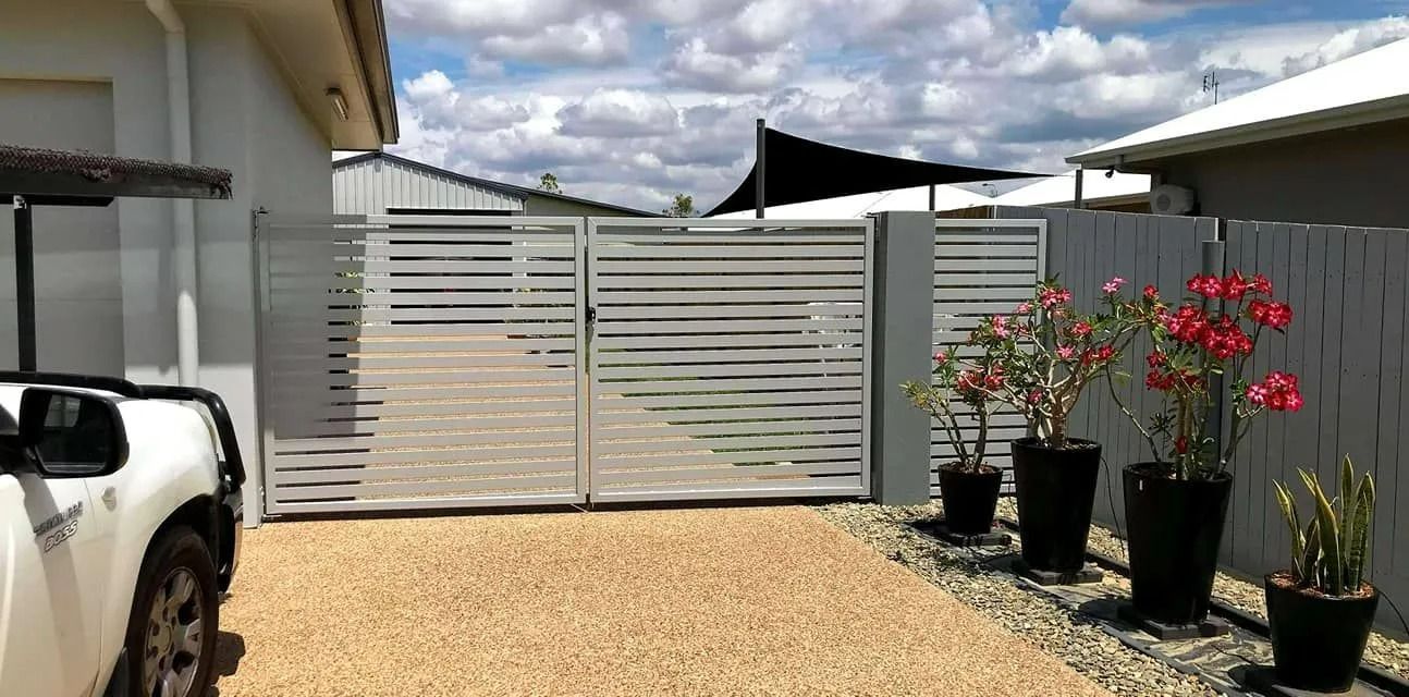 A Gravel Driveway Leads to a Light Grey Horizontal Slat Fence and Gate — Gate-O-Matic in Garbutt, QLD
