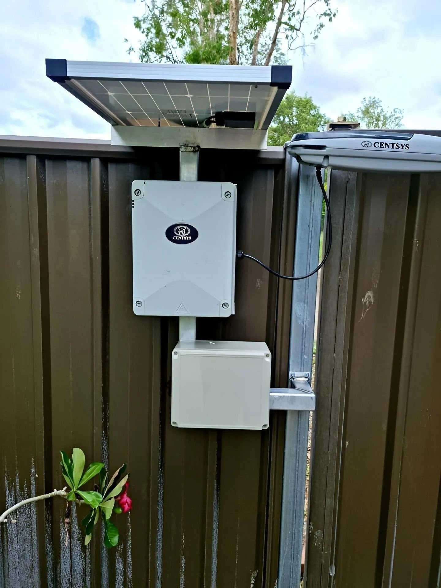 Solar Panel and Control Boxes Mounted on a Brown Fence — Gate-O-Matic in Garbutt, QLD
