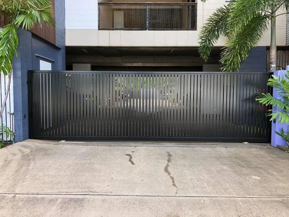 Black Metal Sliding Gate in Front of a Modern Building — Gate-O-Matic in Garbutt, QLD