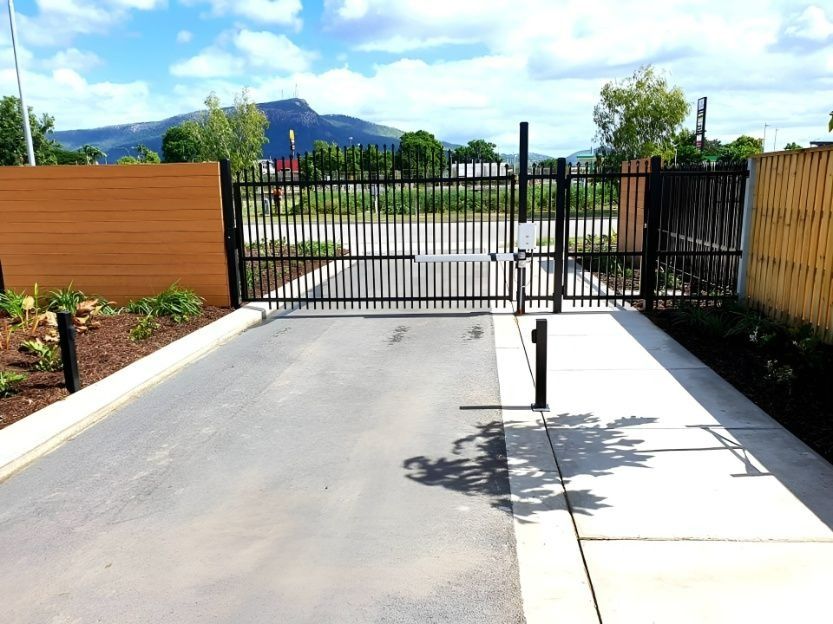 Black Gate With Barrier Arm Over Asphalt Driveway — Gate-O-Matic in Garbutt, QLD