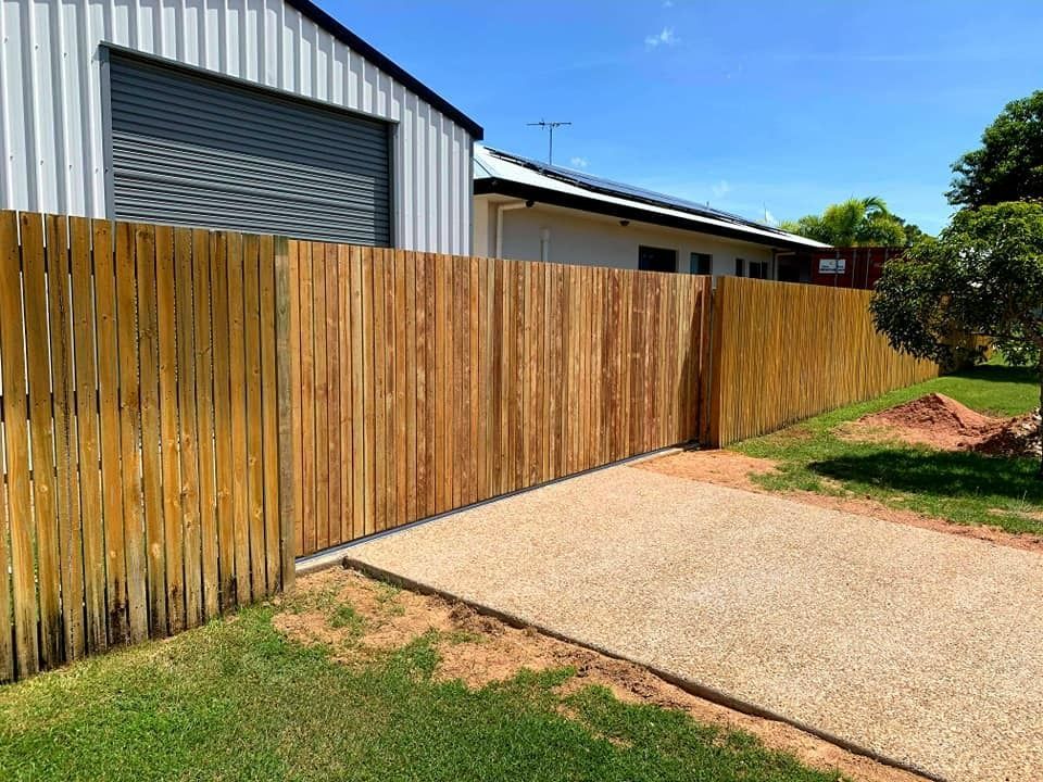 Wooden Fence Along a Gravel Driveway in Front of a Shed and House on a Sunny Day — Gate-O-Matic in Garbutt, QLD
