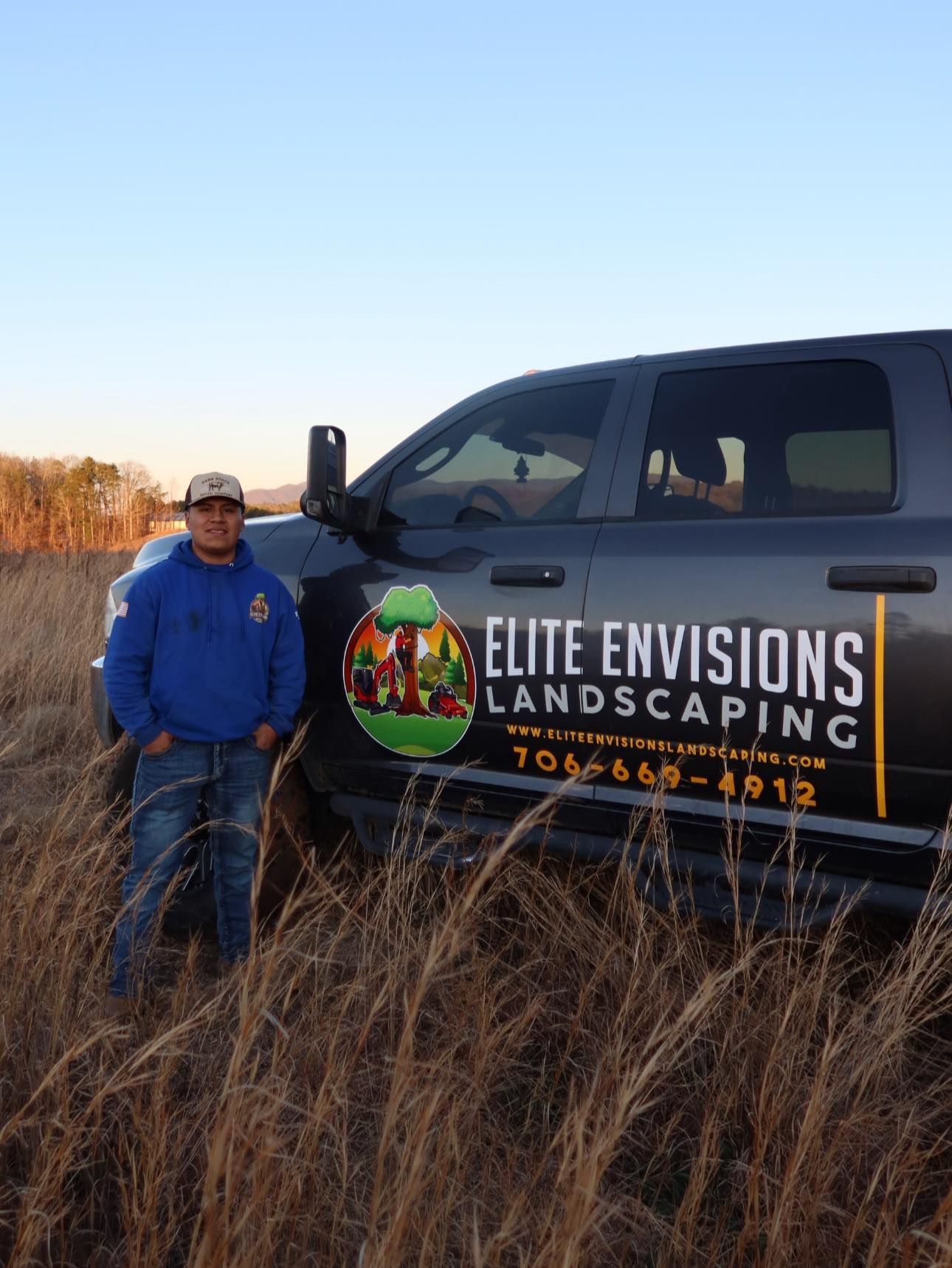 A person stands beside a dark pickup truck with 