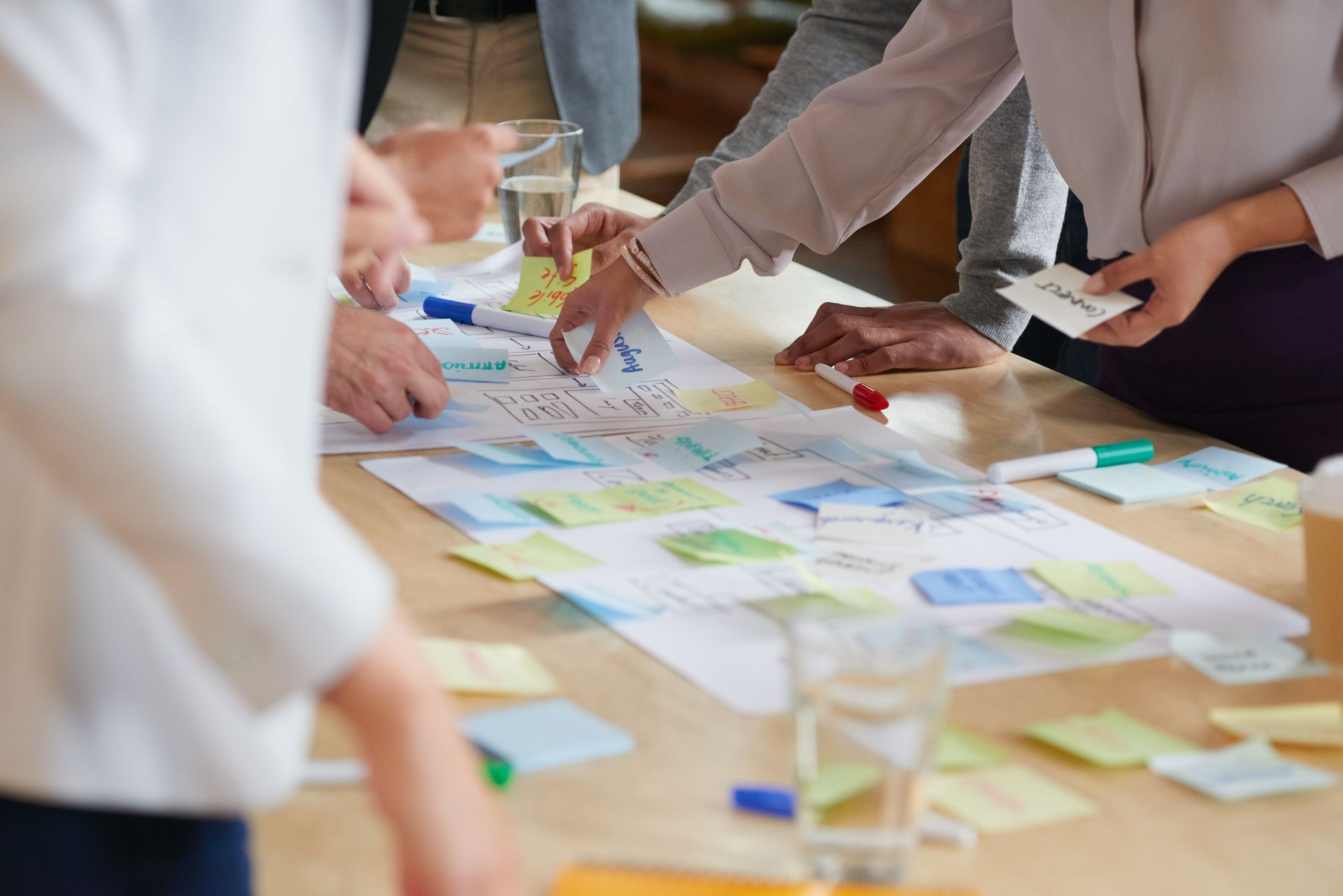 People collaborating around a table covered with colorful sticky notes and paper sketches