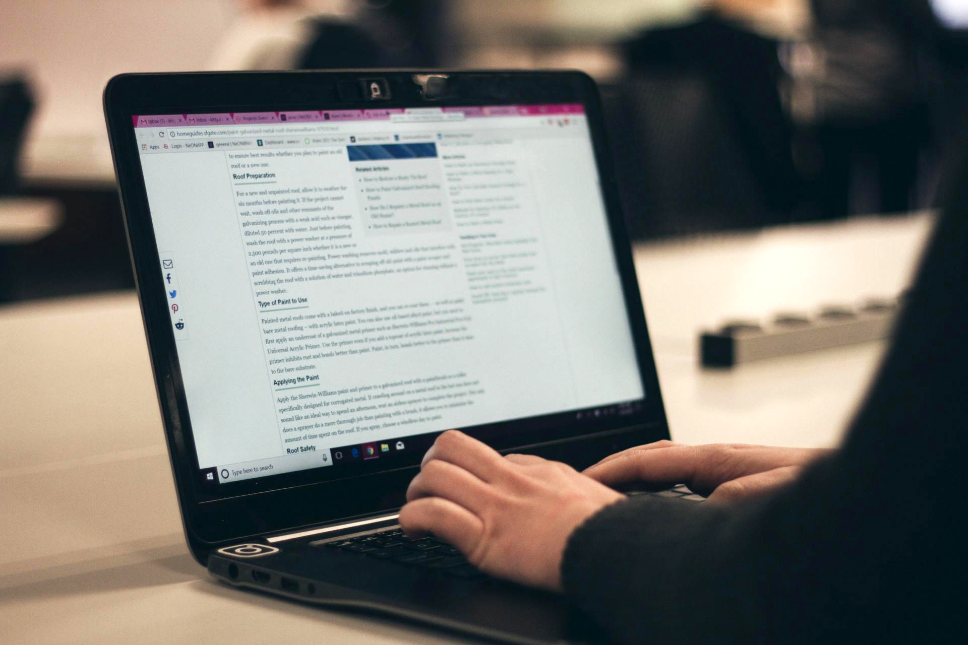 Person typing on a laptop with a document open on screen in a dim office setting