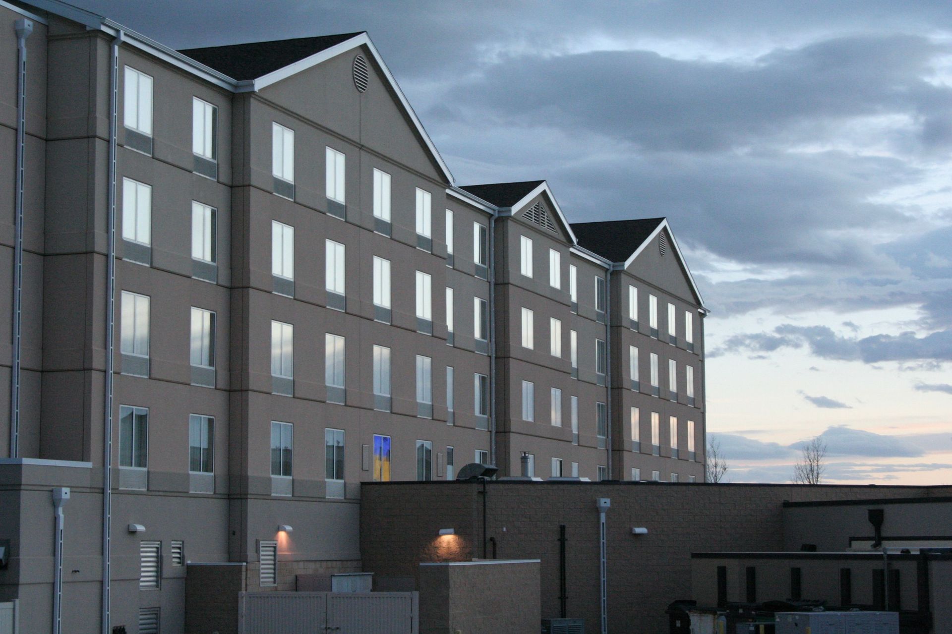 Multi-story gray apartment building at dusk under a cloudy sky