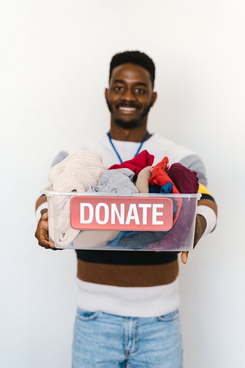 A man is holding a plastic container filled with clothes.