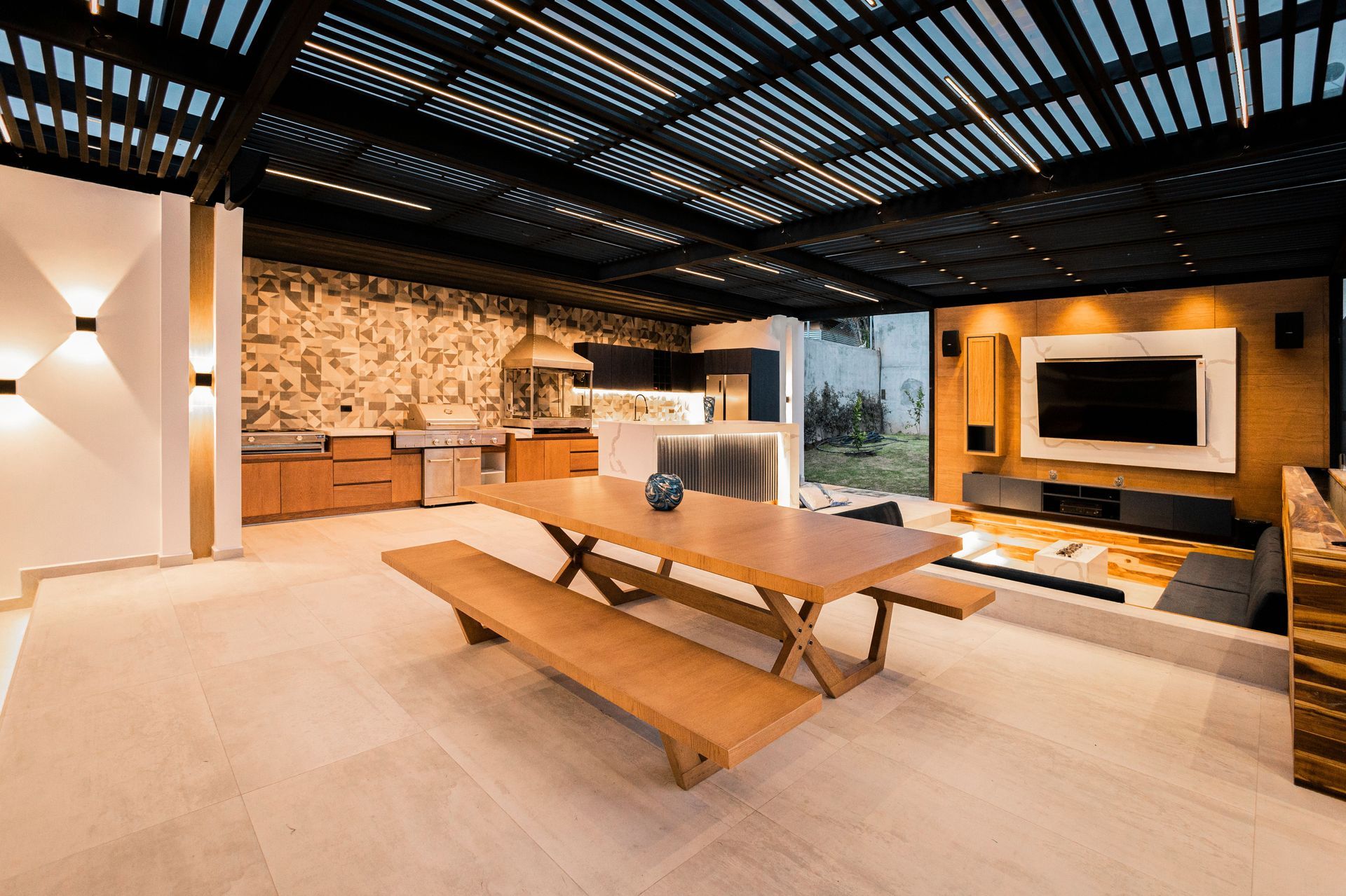 Modern lounge with wooden table, slatted ceiling, stone wall, and wall-mounted TV in warm lighting