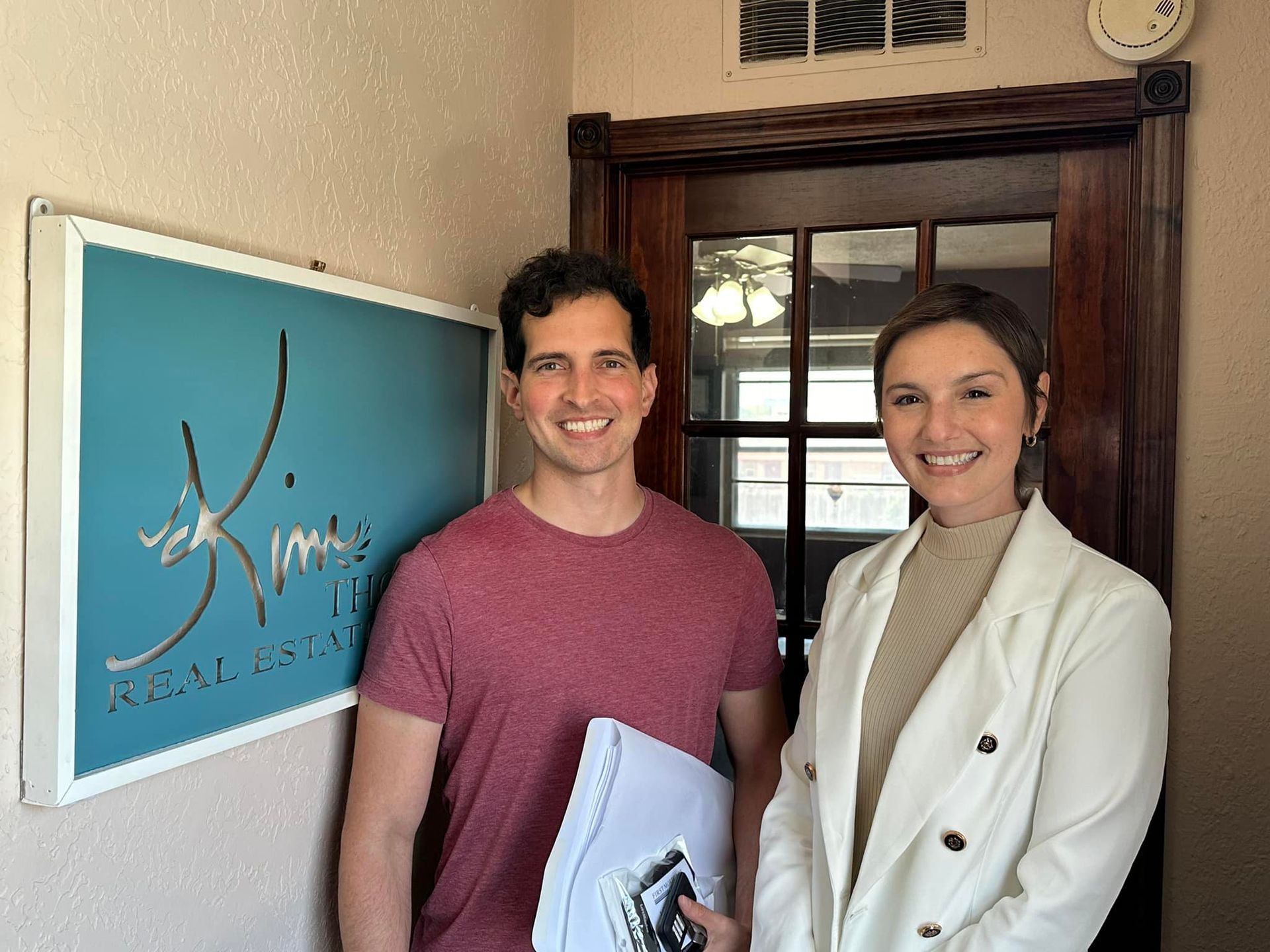 Two people stand by a turquoise sign that reads 