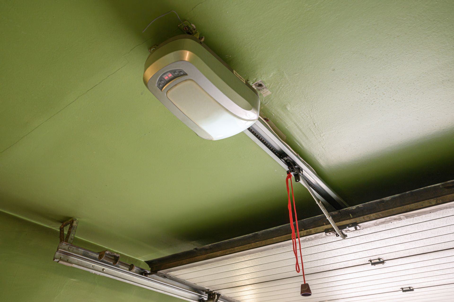 Garage ceiling with a white garage door opener and metal track on a green ceiling