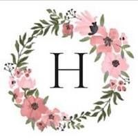 Floral wreath of pink flowers and green leaves surrounding a black letter H on a white background