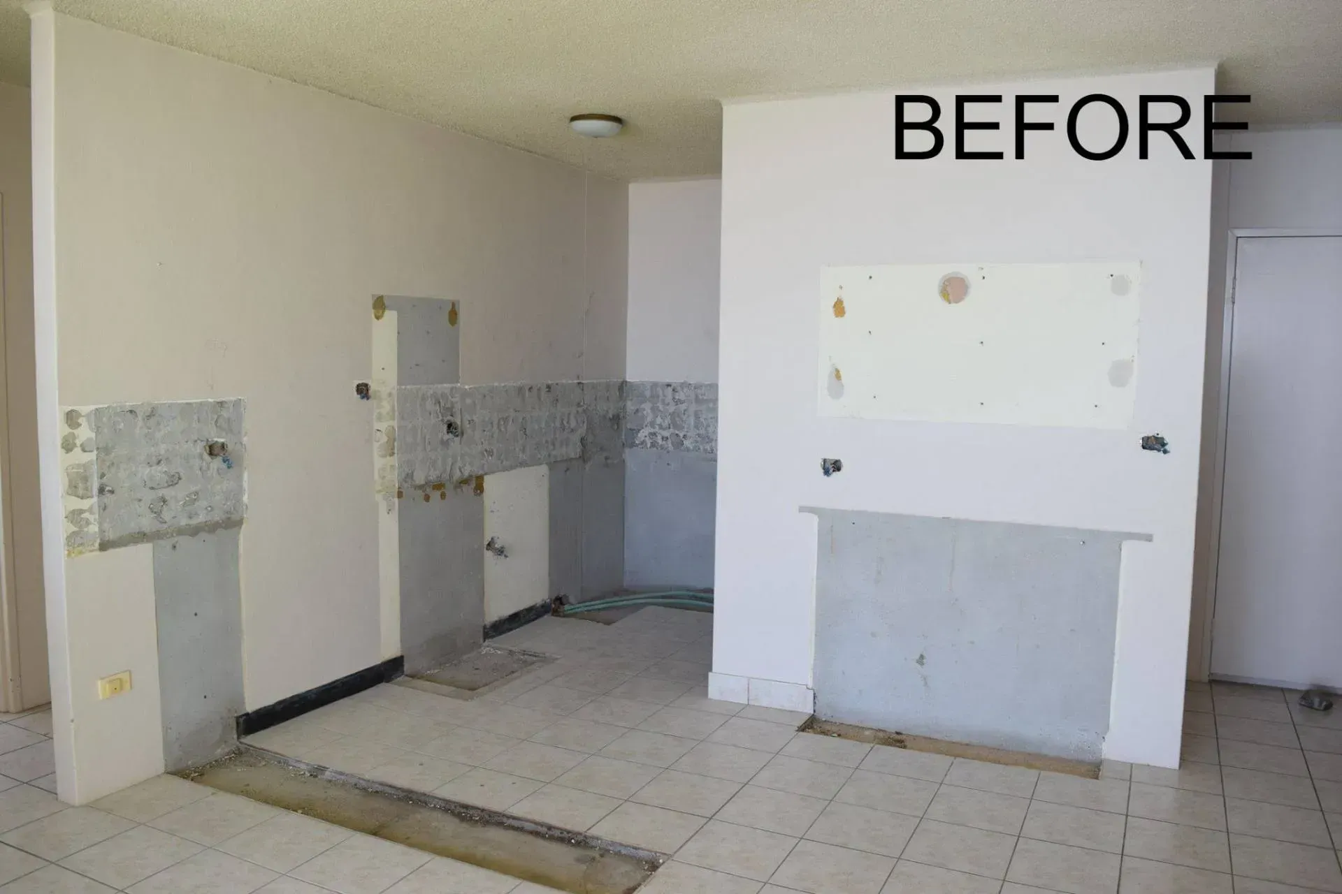 Kitchen renovation: walls stripped of tile and cabinets; light gray tile floor. 