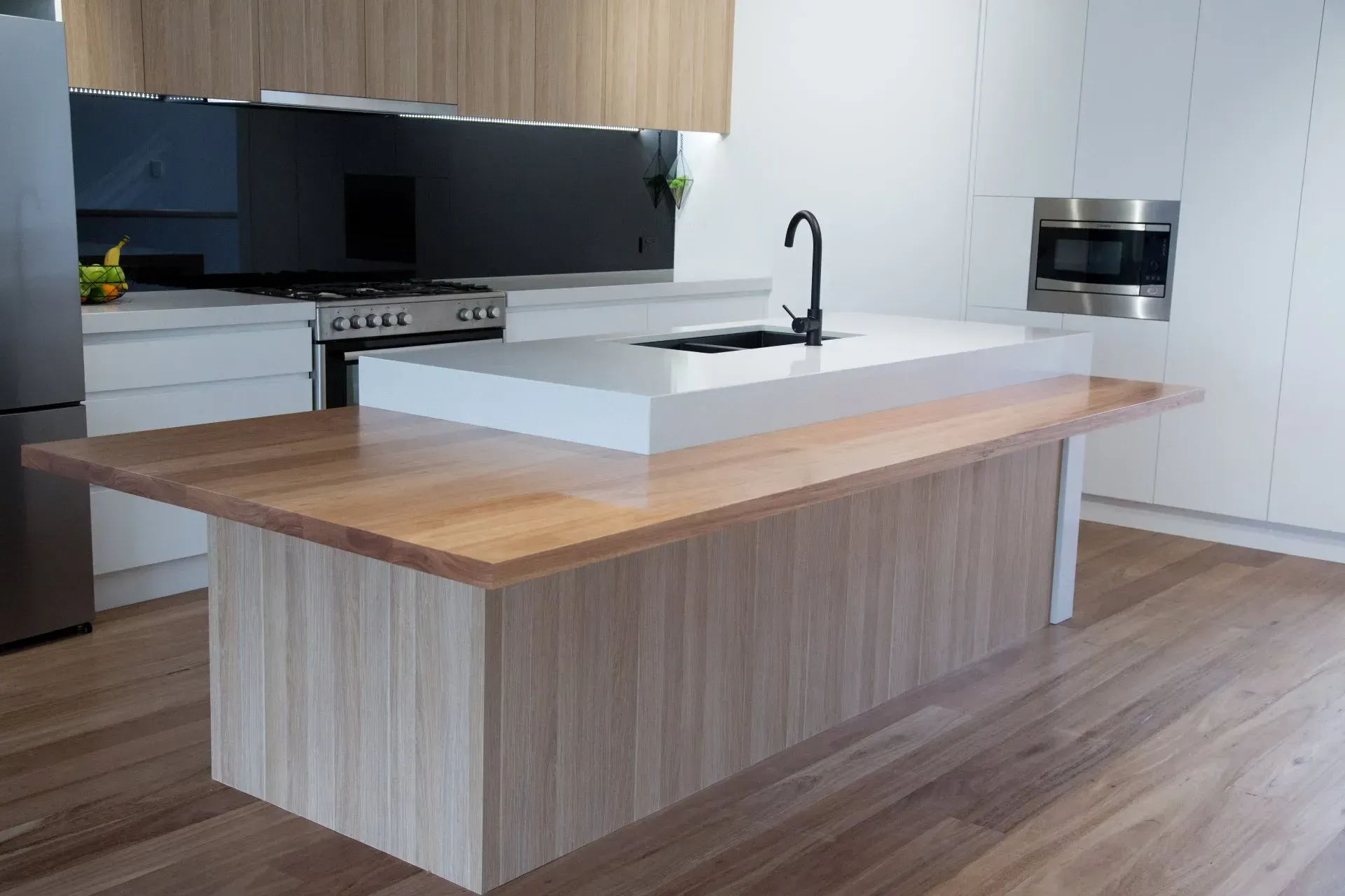 Kitchen with light wood island and countertop, white cabinets, and stainless steel appliances.
