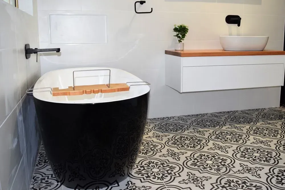 Modern black and white bathroom with a freestanding tub, patterned floor, and floating vanity.