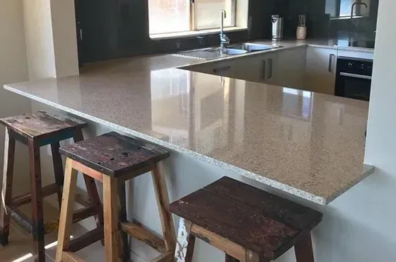 Kitchen with granite countertop and three rustic stools.