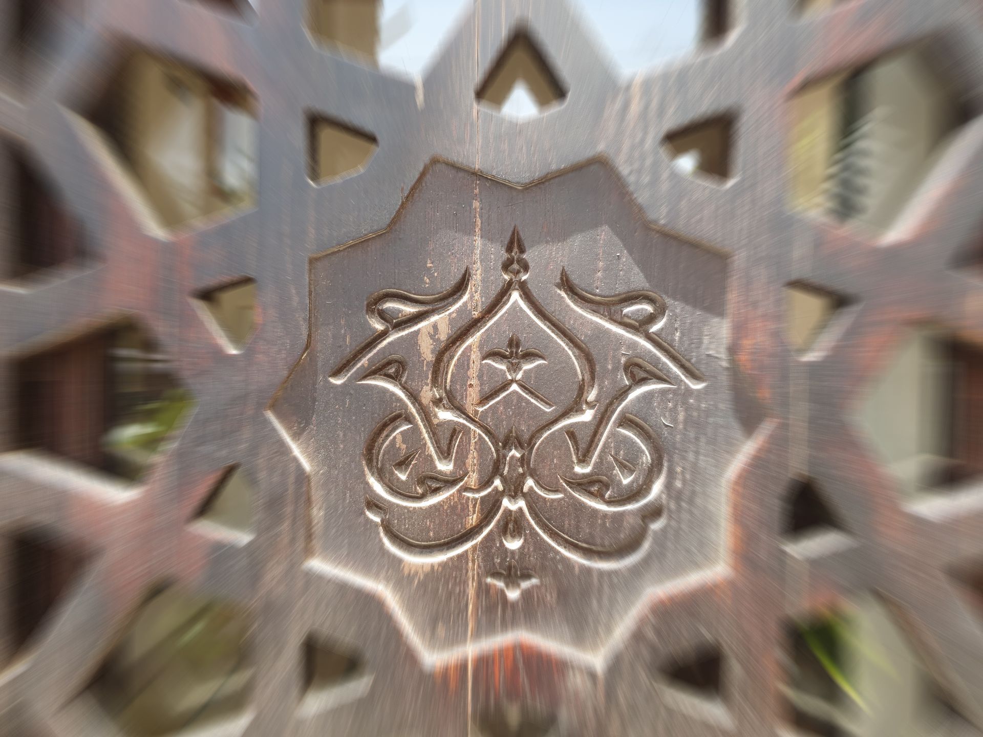 Intricate wooden carving with central floral design within an eight-pointed star shape.