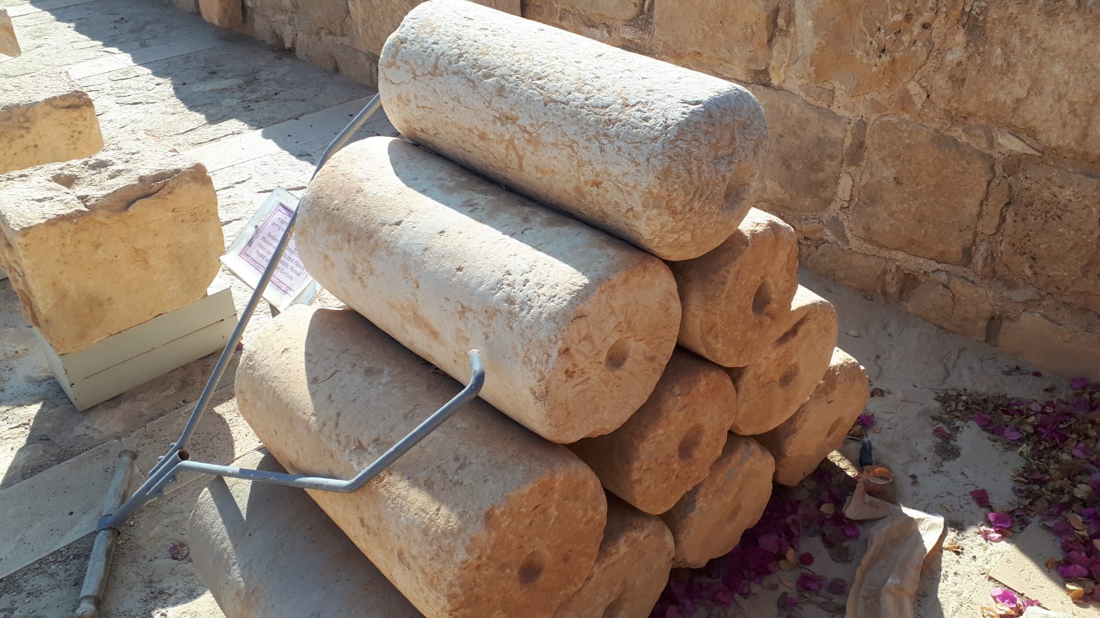 A stack of cylindrical, light-colored stone blocks on a sunny, stone surface.