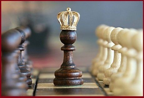 Chessboard with a crowned black king facing white pawns.