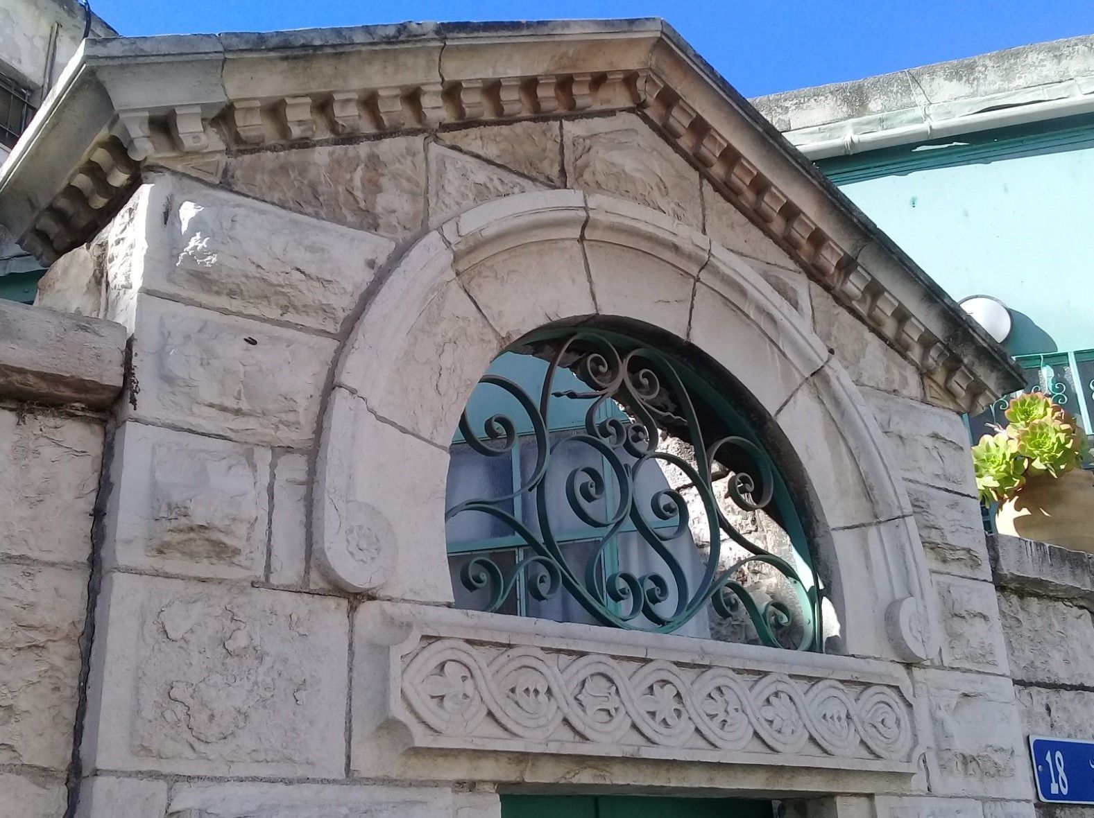 Stone building with arched window detail, steps leading up to the front entrance. Trees in front.