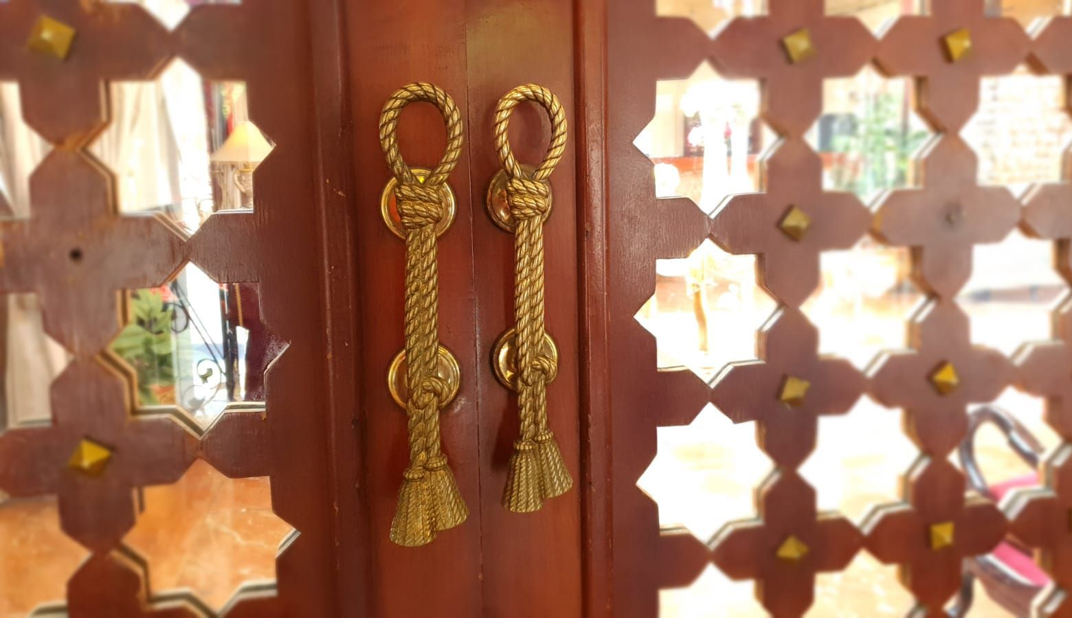 Ornate wooden door with gold rope-style handles and decorative cutouts.