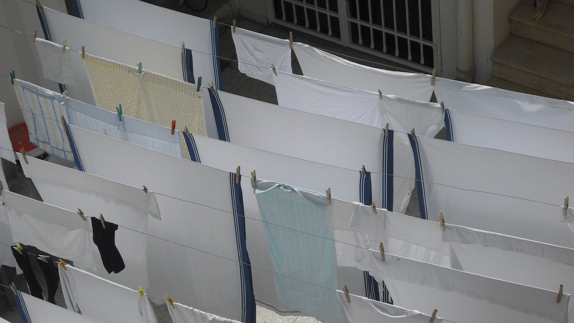 Laundry hanging on lines, white sheets and clothing drying outdoors.