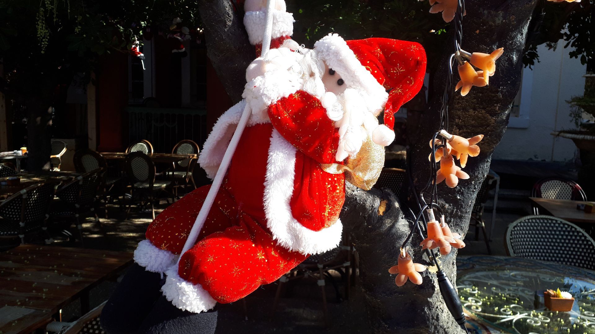 Santa Claus decoration hanging from a tree, red suit with white trim.