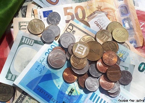 Close-up of assorted foreign banknotes and coins, including Euros, US dollars, and Israeli shekels.