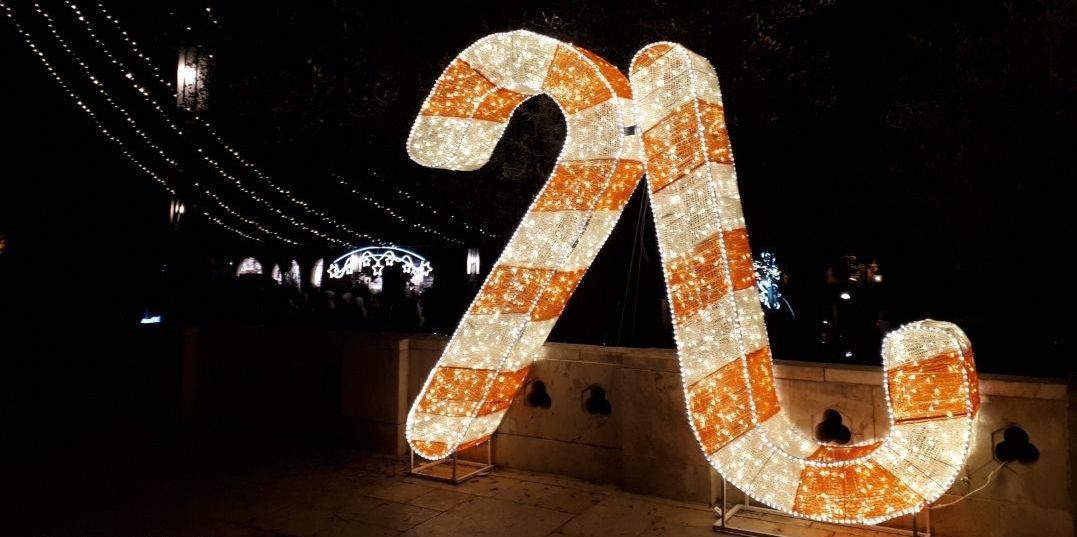 Large, illuminated candy canes on display at night, orange and white stripes.