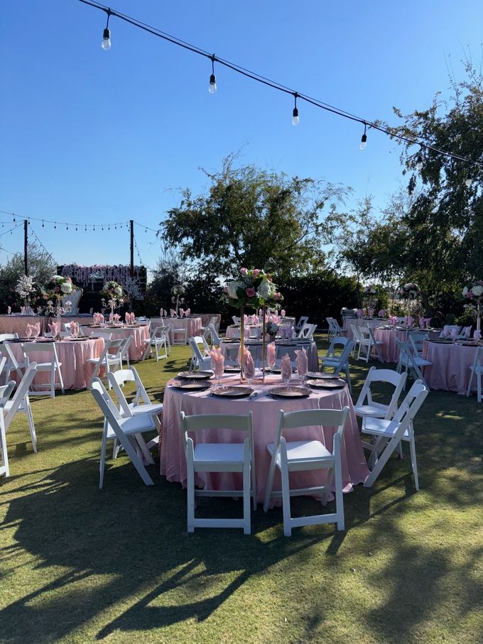Two servers setting a long outdoor dining table with flowers and champagne.