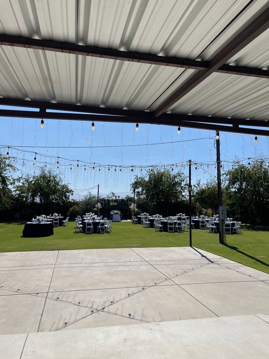 Outdoor wedding ceremony with floral arch and rows of white chairs.