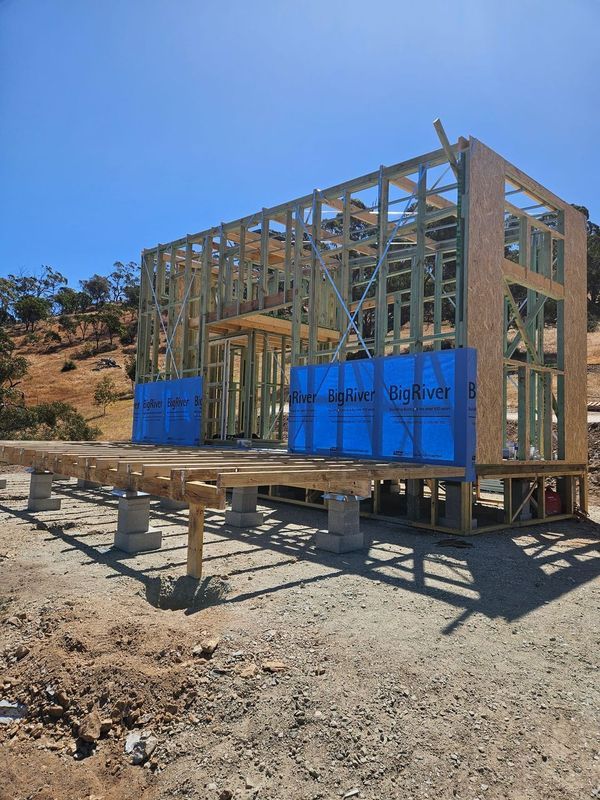 A house is being built in the middle of a dirt field.