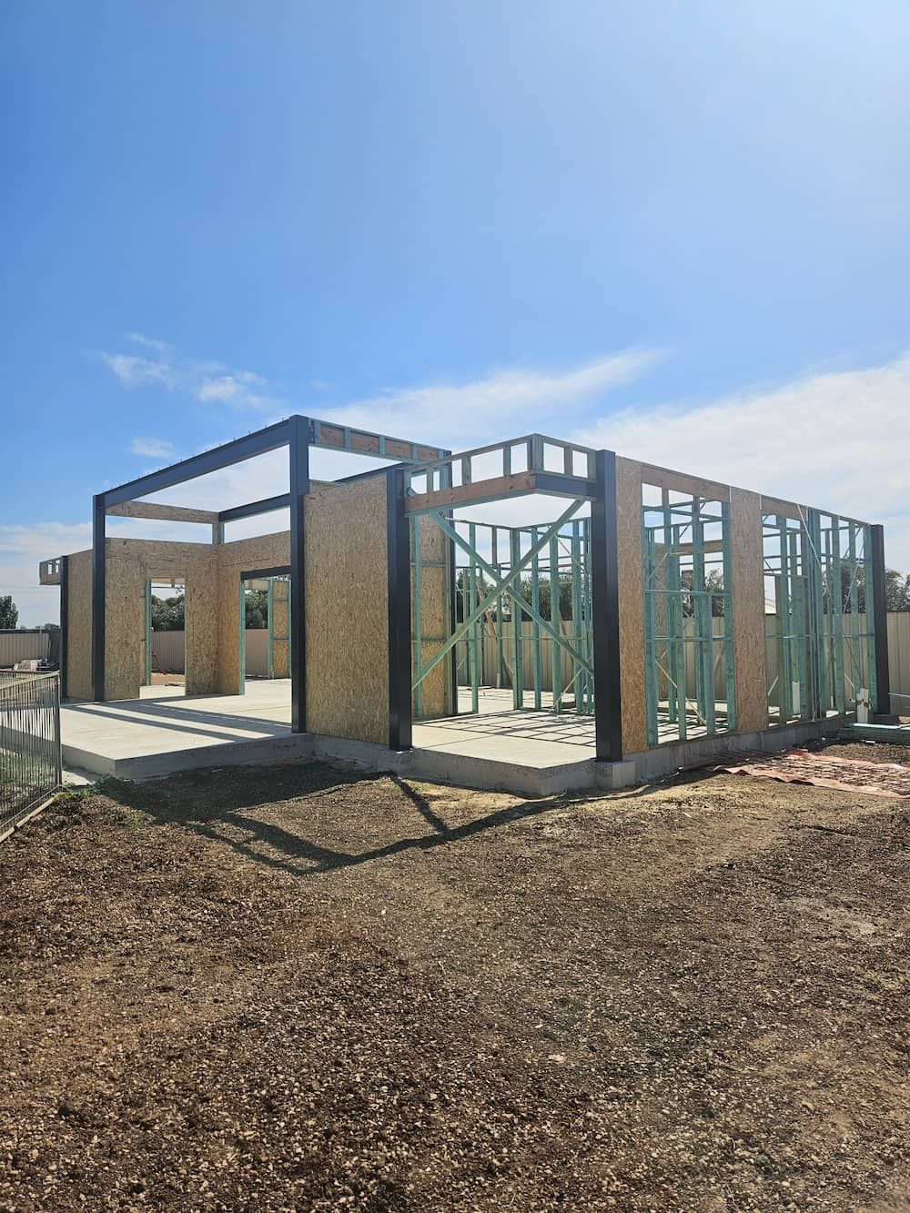 A house is being built in a field with a blue sky in the background.