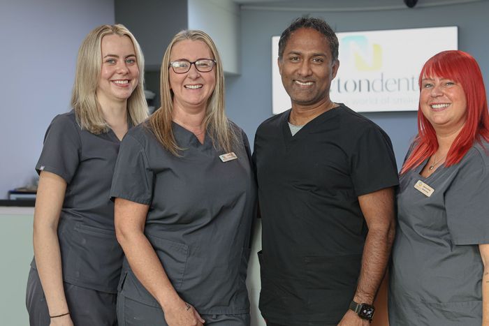 A man and two women are posing for a picture together. Dental professionals