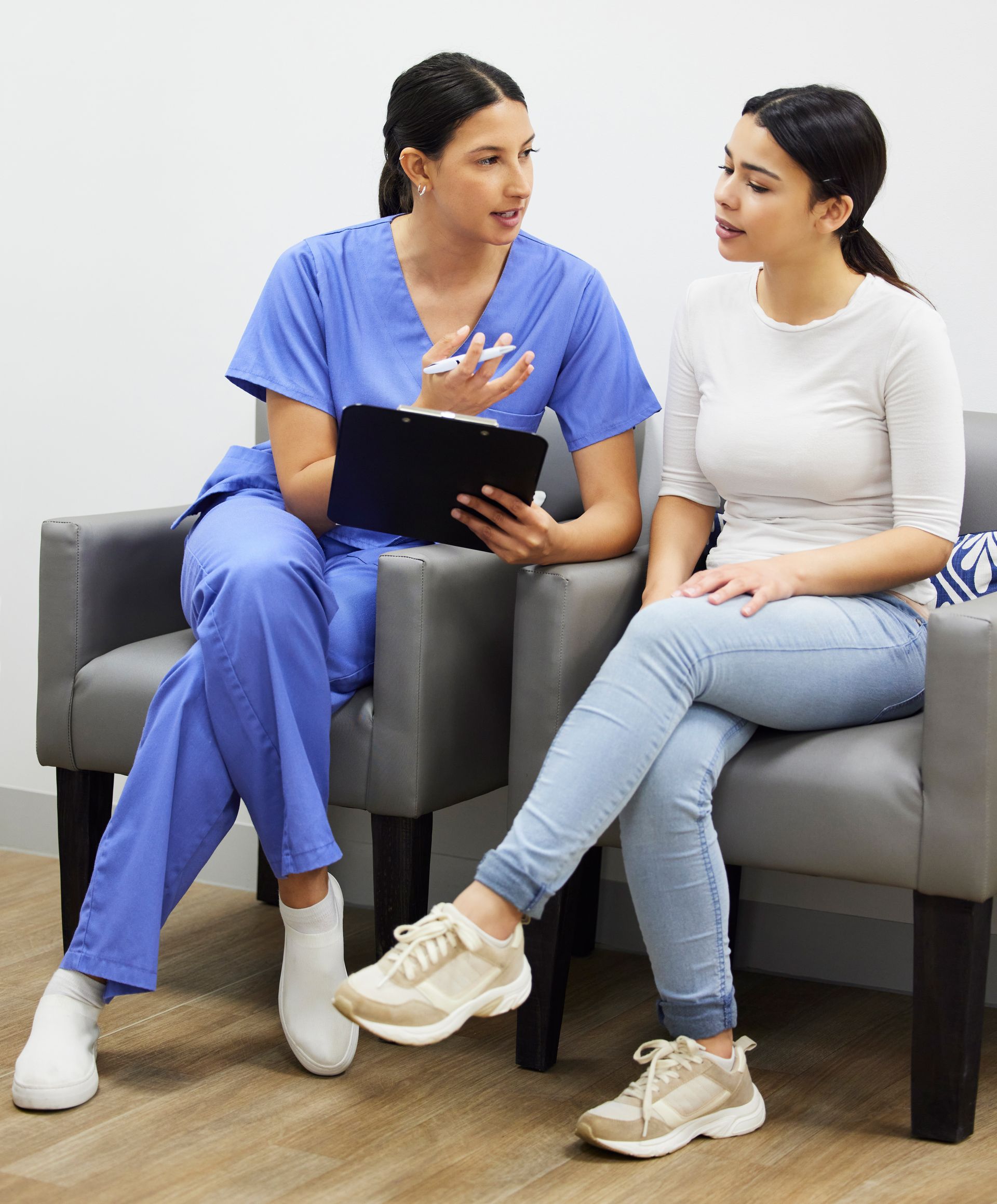 A nurse is talking to a patient in a waiting room, discussing treatment and finance.