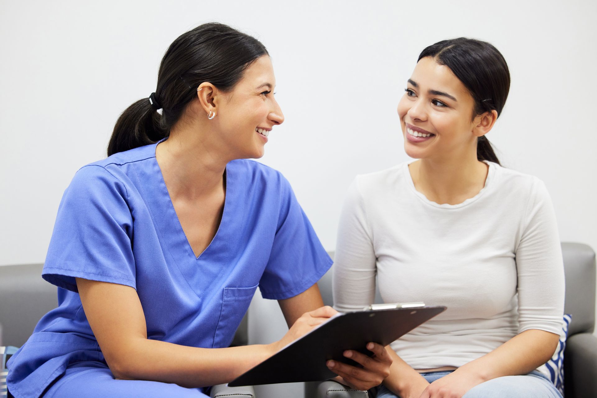 A nurse is talking to a patient while holding a clipboard.