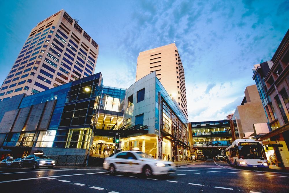 A Car is Driving Down a Street in Front of a Building — Bondi Removals and Taxi Trucks in Bondi Junction, NSW