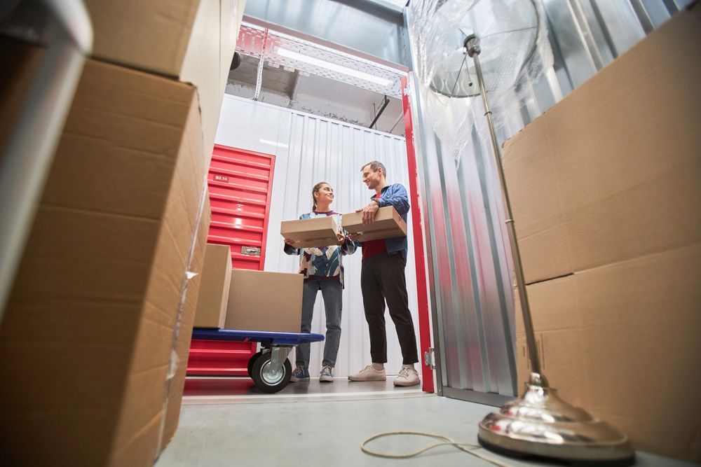 A Man and a Woman Are Carrying Boxes in a Storage Unit — Bondi Removals and Taxi Trucks In Woollahra, NSW