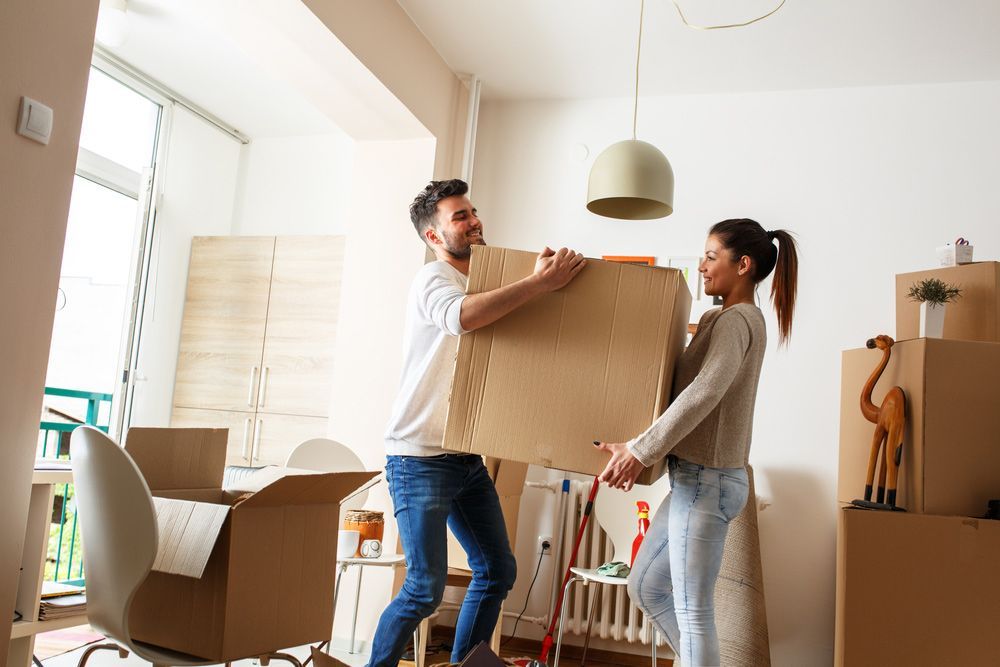 A Man and A Woman Are Carrying Boxes Into a New Home — Bondi Removals and Taxi Trucks in Bondi Junction, NSW