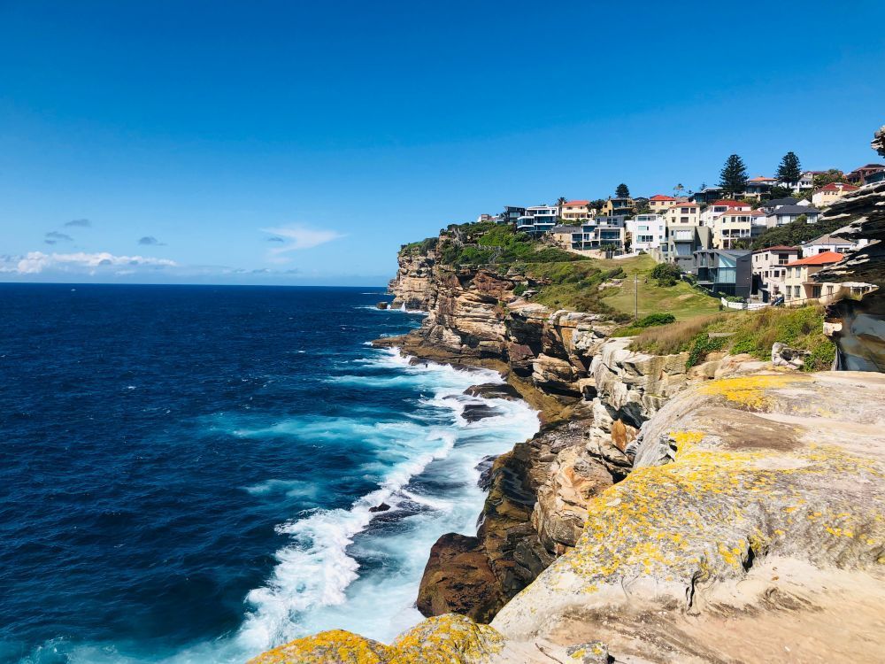 A View of a Cliff Overlooking the Ocean With Waves Crashing on the Shore — Bondi Removals and Taxi Trucks in Dover Heights, NSW