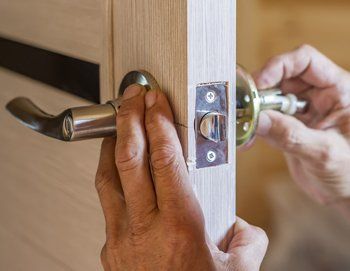 man repairing the doorknob. closeup of worker's hands installing new door locker