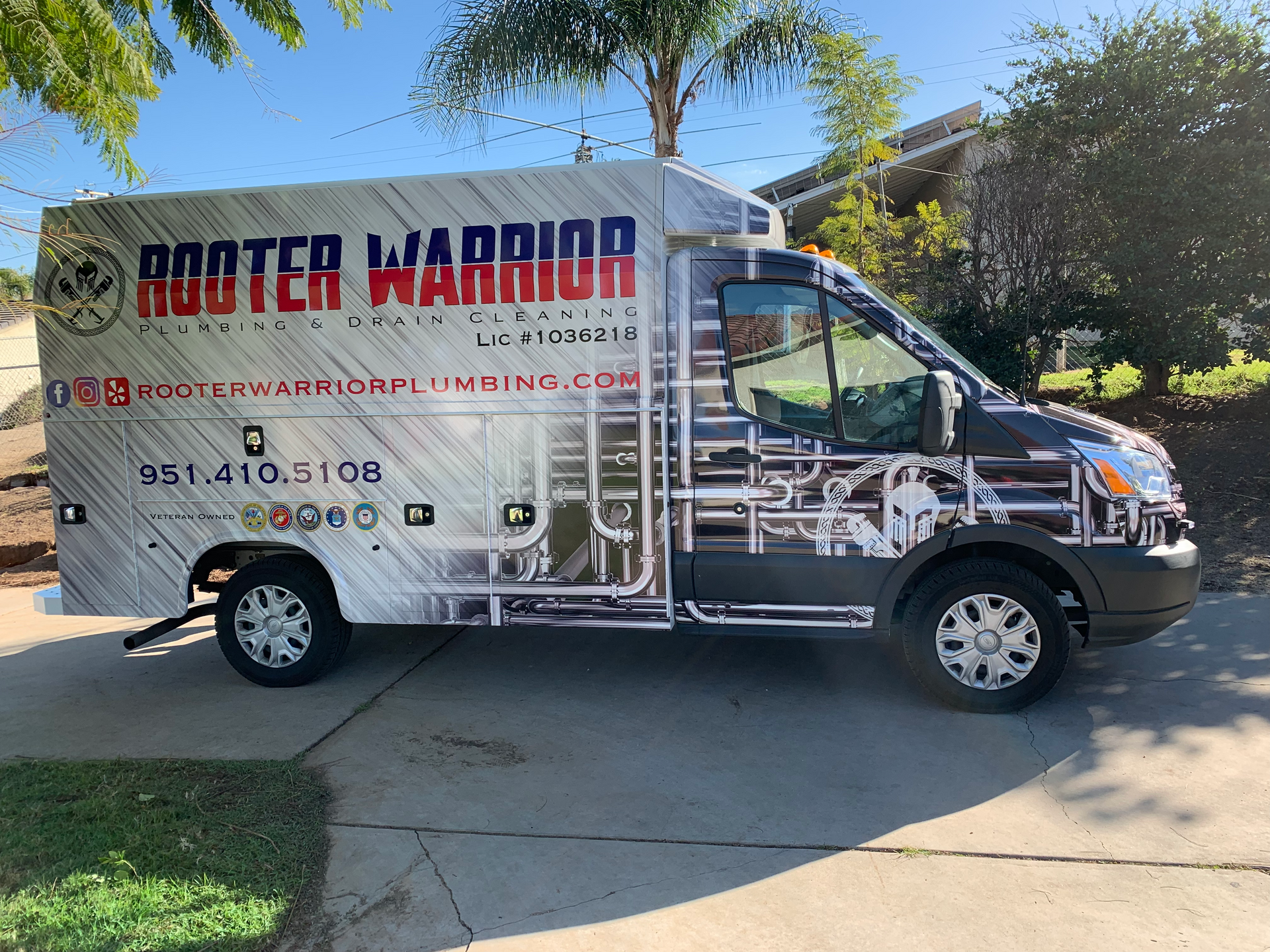 Silver “ROTOR WARRIOR” utility truck parked in a driveway, side view with palm trees in the background