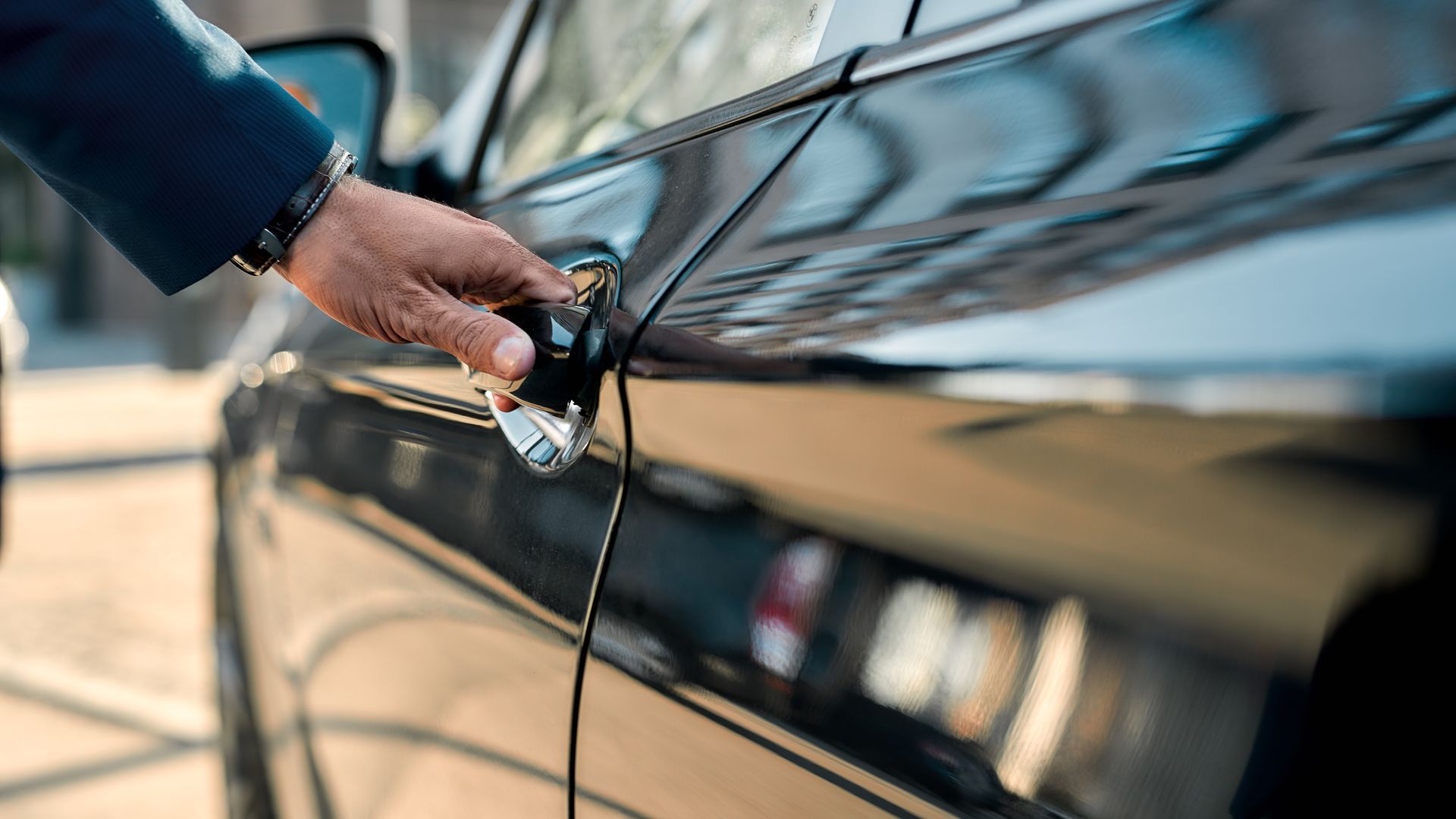 Hand plugging an electric vehicle into a charging port on a glossy black car