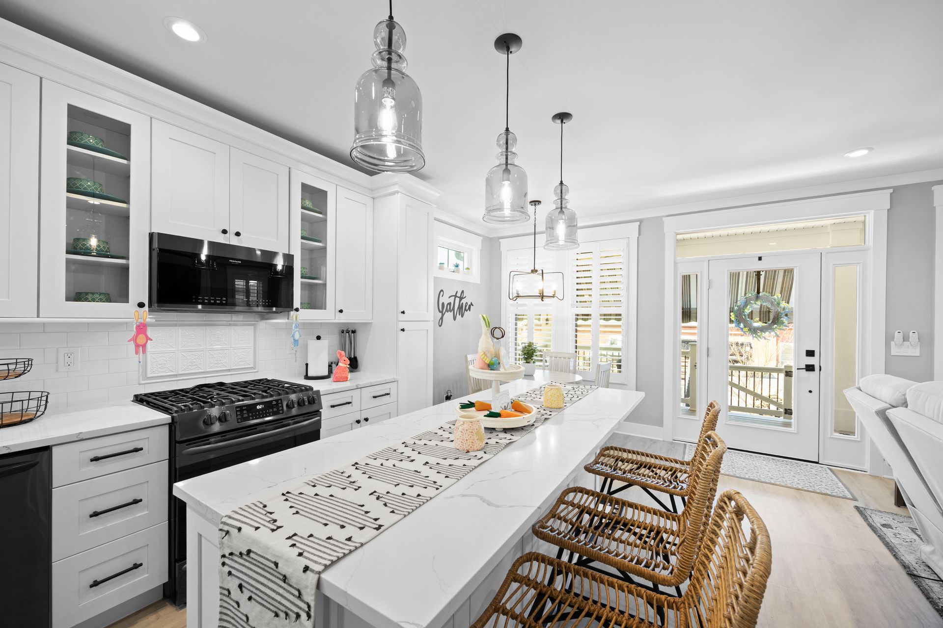 Bright white modern kitchen with island seating, pendant lights, and sliding doors to a patio.