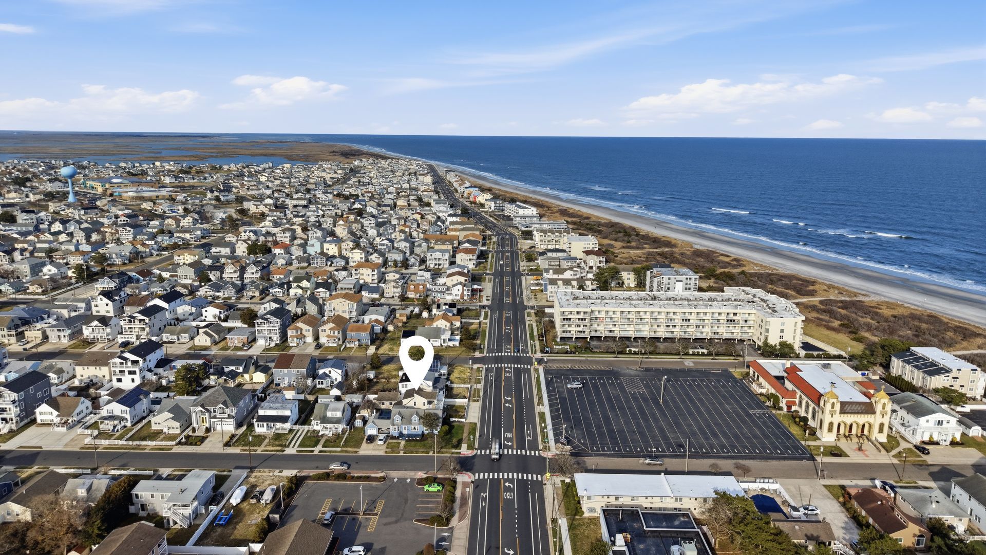 Aerial view of a coastal neighborhood with rows of houses beside a beach and ocean