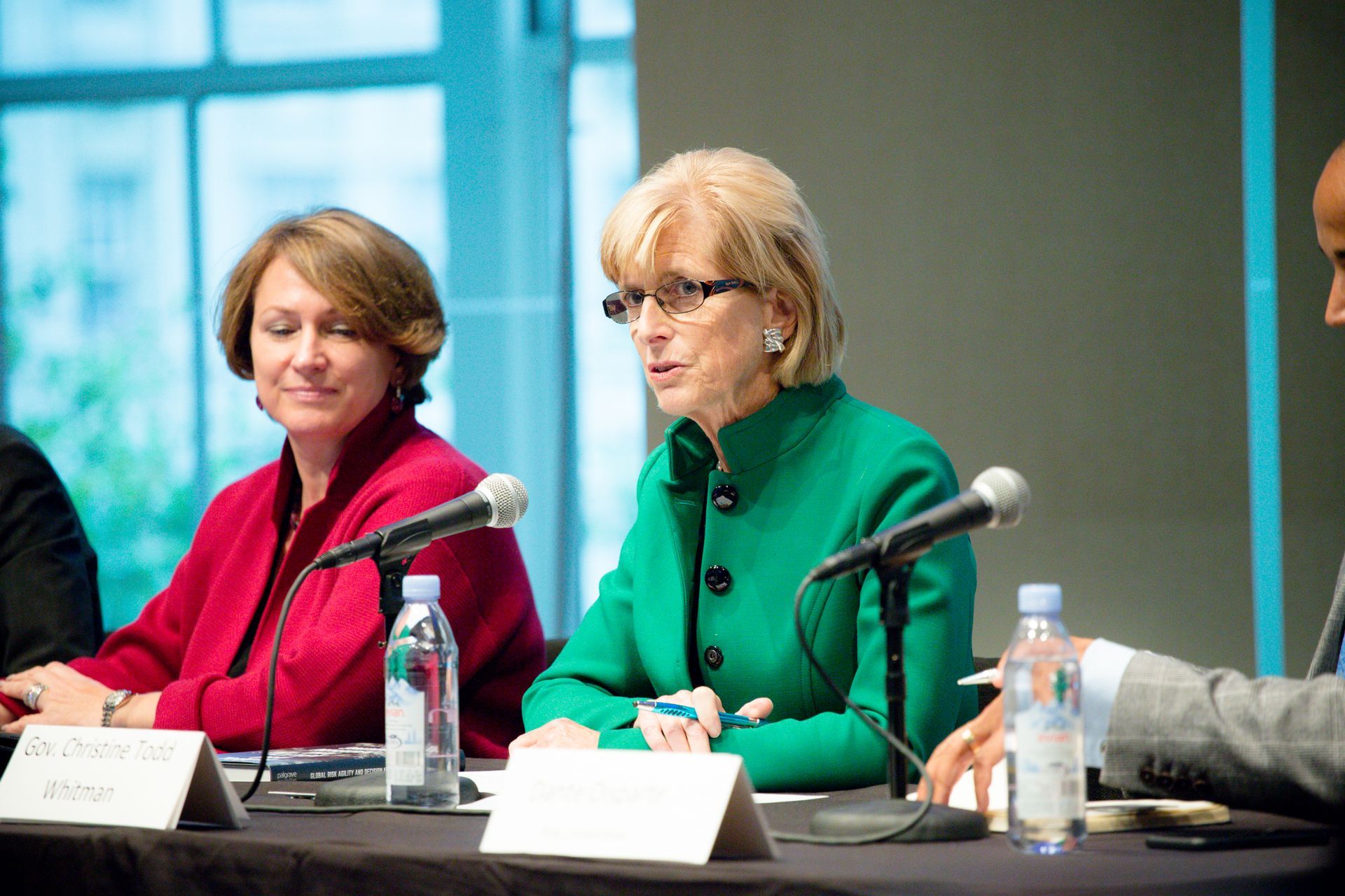 Panel discussion with three people seated at a table, speaking into microphones at a conference.