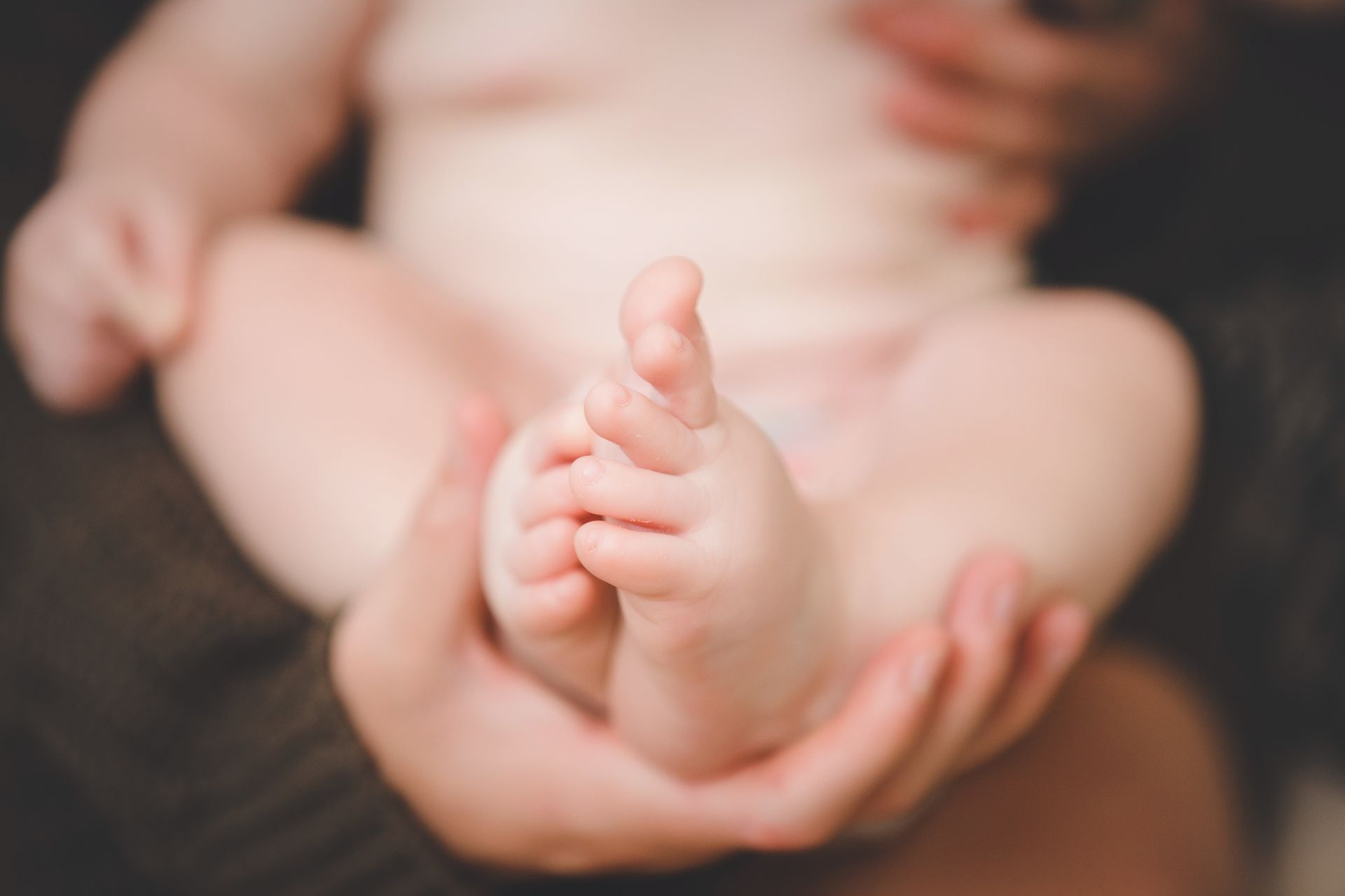 Close-up of a baby’s feet being gently held in adult hands