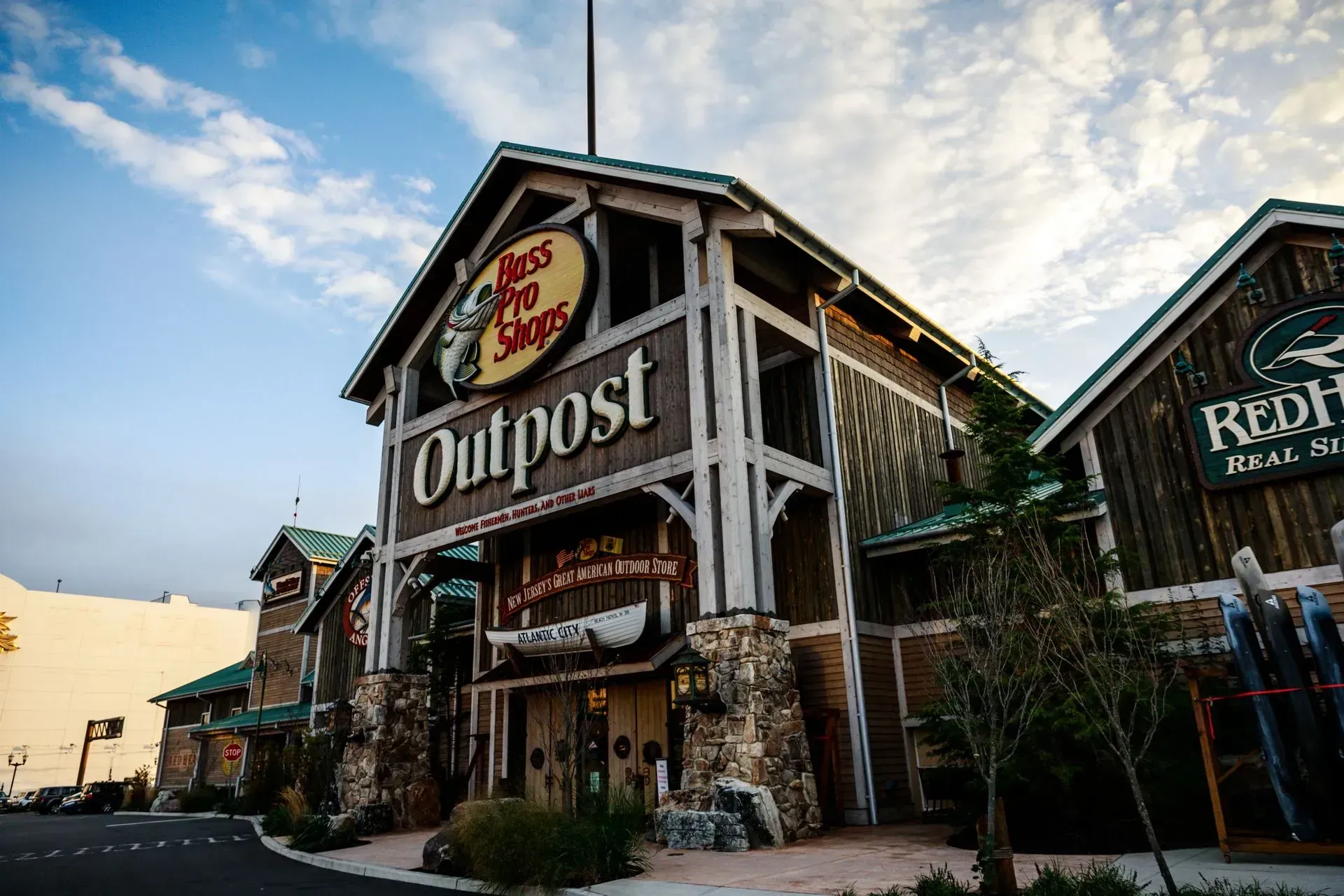 Rustic Outpost storefront at dusk with wooden facade and outdoor plants under a cloudy sky