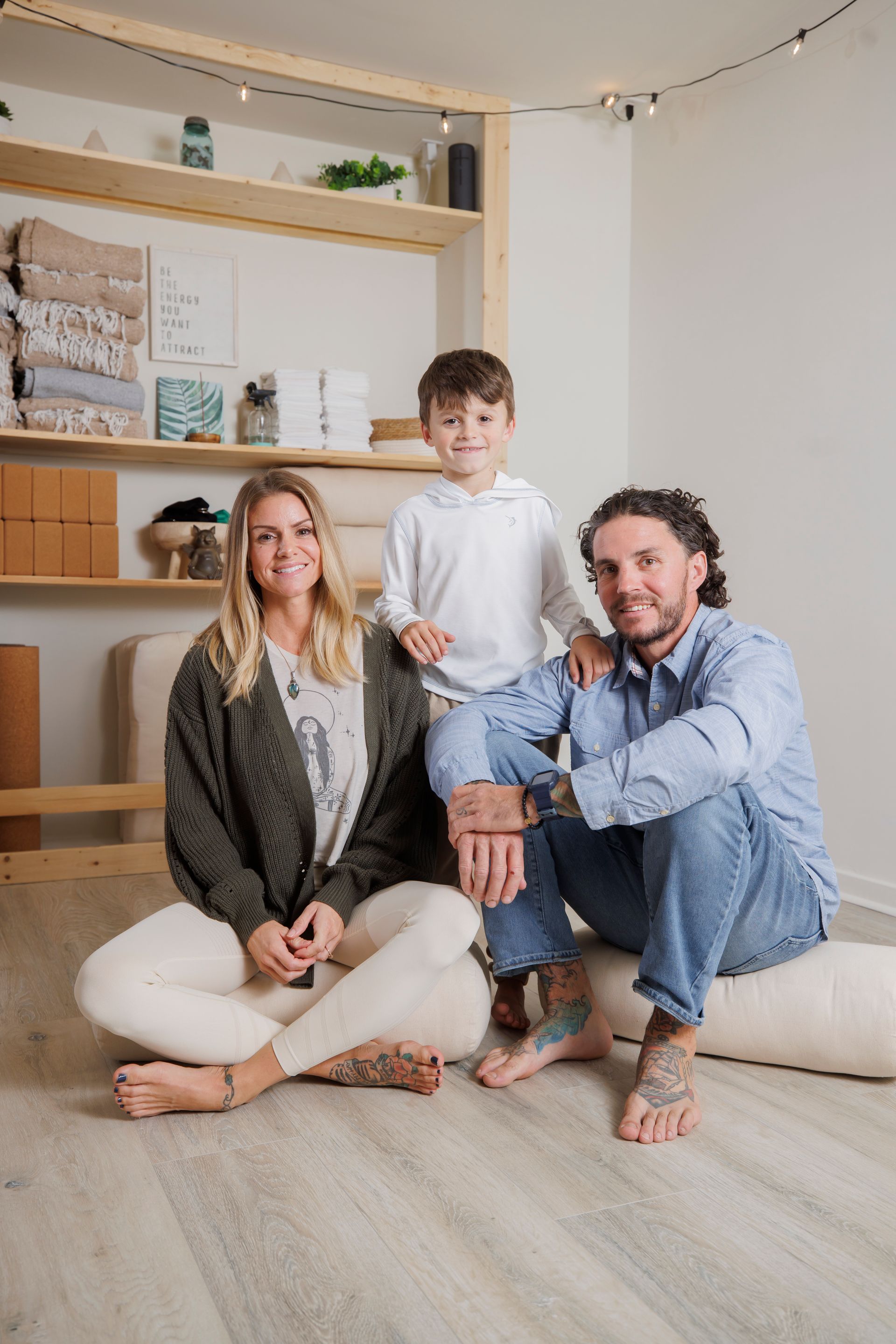 Family seated on the floor in a bright, cozy room with shelves and soft neutral decor